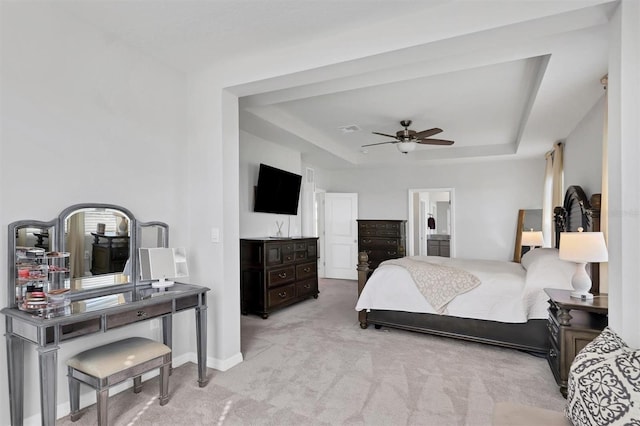 bedroom featuring ceiling fan, a raised ceiling, light carpet, and ensuite bath