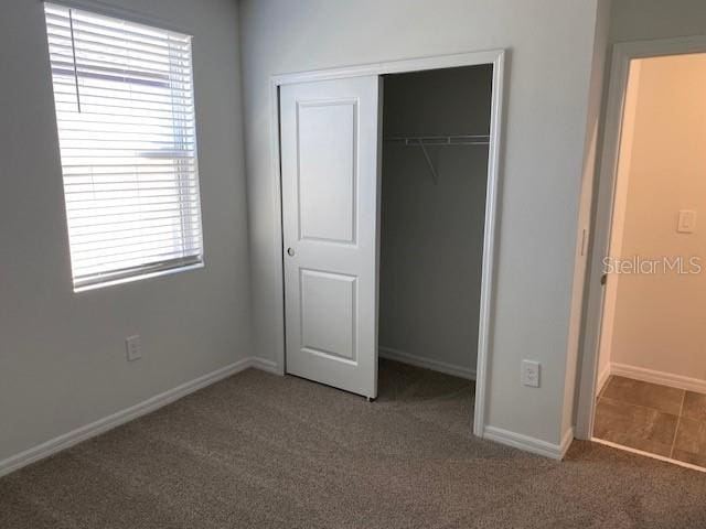 unfurnished bedroom featuring dark colored carpet and a closet