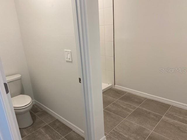 bathroom featuring tile patterned flooring, toilet, and walk in shower