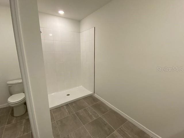 bathroom with a tile shower, tile patterned floors, and toilet