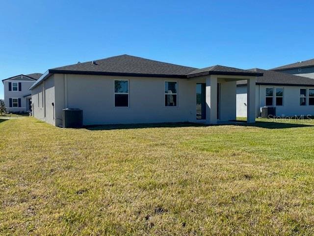 rear view of property with a lawn and cooling unit