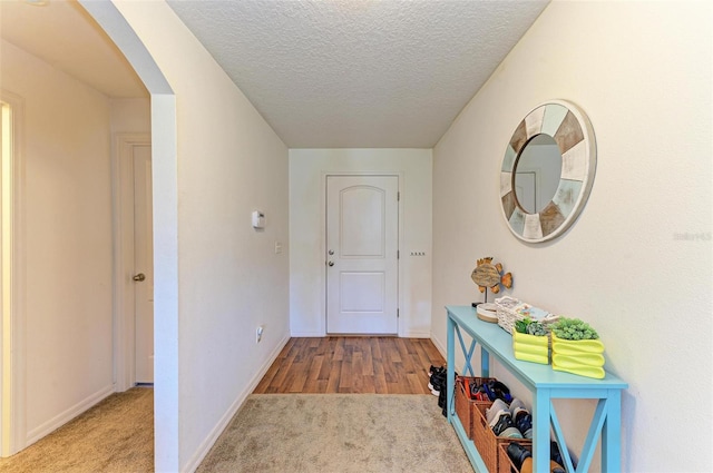 hallway with a textured ceiling and light wood-type flooring