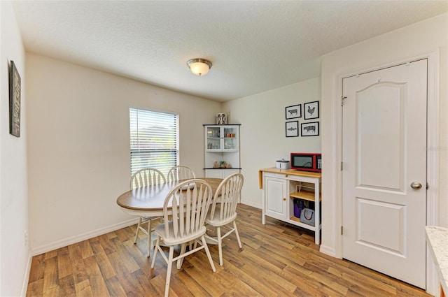 dining room with a textured ceiling and light wood-type flooring