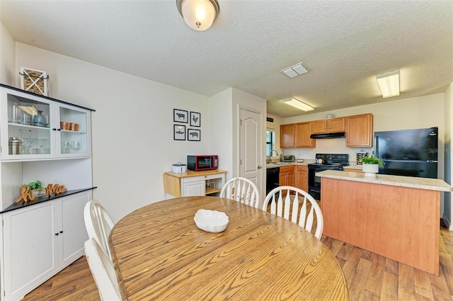 dining space with a textured ceiling, light wood-type flooring, and sink