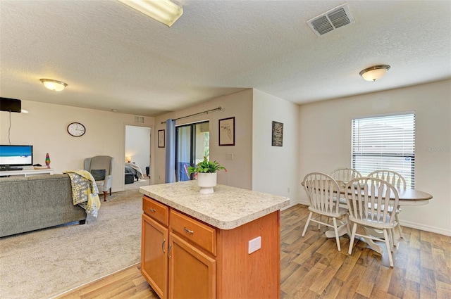 kitchen with a center island, light hardwood / wood-style floors, and a textured ceiling