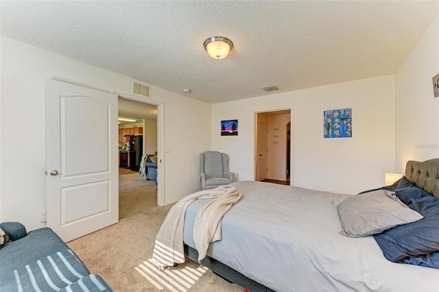 bedroom featuring a textured ceiling, black fridge, and light carpet