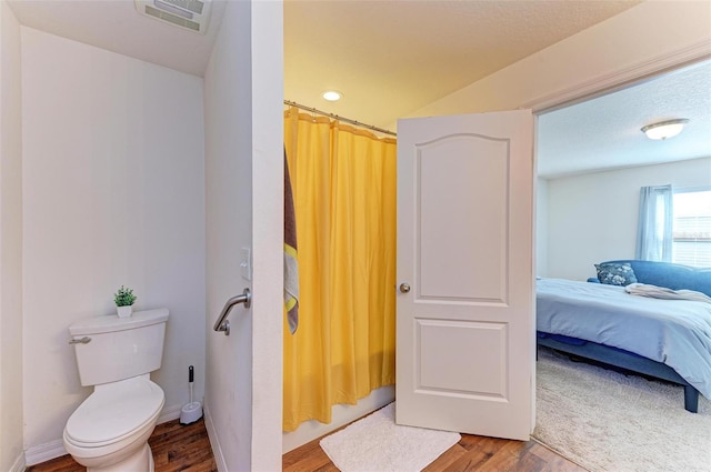 bathroom featuring hardwood / wood-style floors, a shower with shower curtain, and toilet