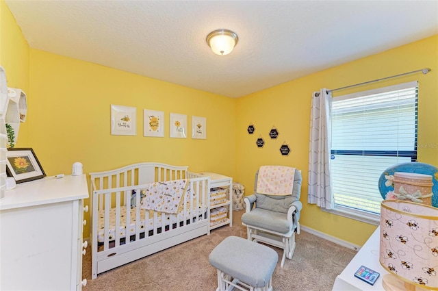 carpeted bedroom featuring multiple windows, a nursery area, and a textured ceiling