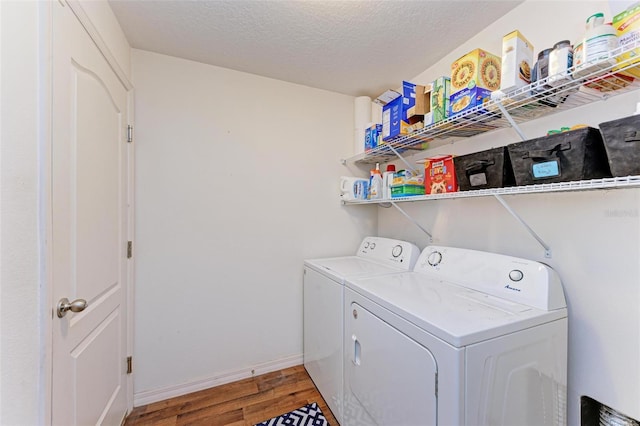 laundry area with wood-type flooring, a textured ceiling, and independent washer and dryer