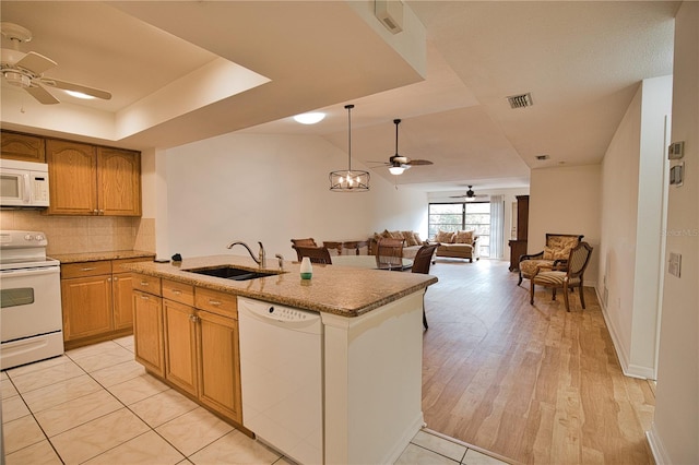 kitchen featuring white appliances, sink, hanging light fixtures, decorative backsplash, and light wood-type flooring