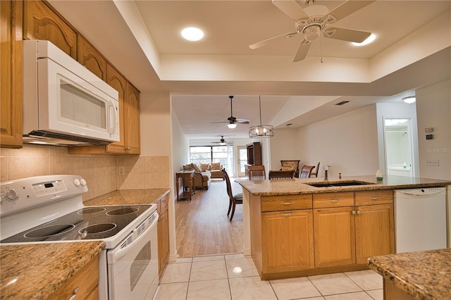 kitchen with pendant lighting, white appliances, sink, light wood-type flooring, and light stone counters