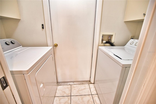 laundry area featuring washer and dryer, light tile patterned floors, and cabinets