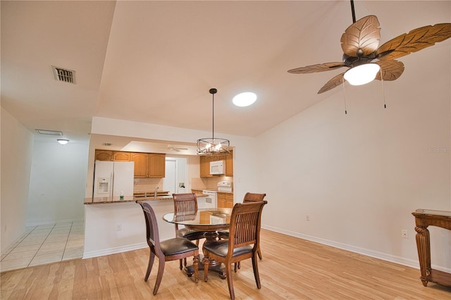 dining area featuring ceiling fan with notable chandelier, light wood-type flooring, lofted ceiling, and sink