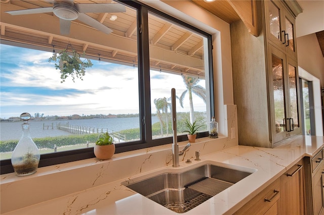 kitchen with light stone countertops, sink, and a water view