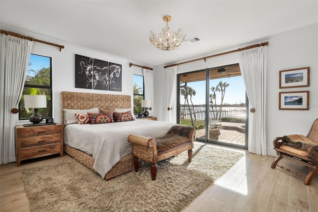 bedroom featuring access to exterior, hardwood / wood-style flooring, and a notable chandelier