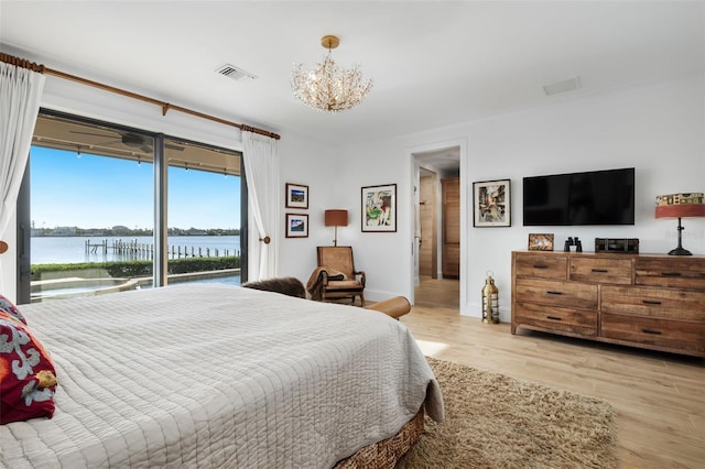 bedroom featuring a chandelier, access to outside, a water view, and light hardwood / wood-style floors