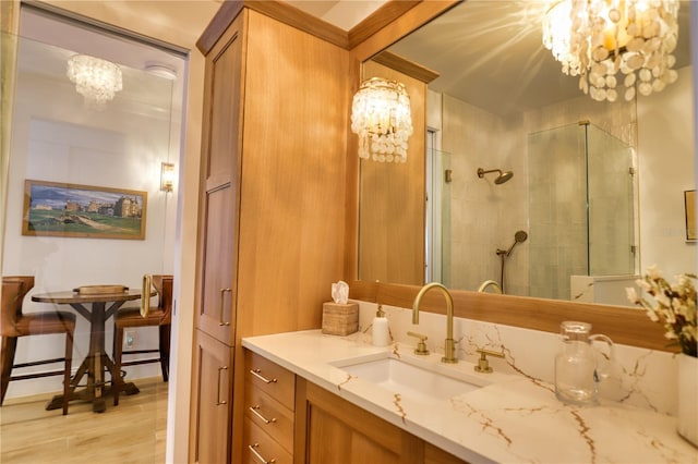 bathroom with a tile shower, vanity, a notable chandelier, and hardwood / wood-style floors