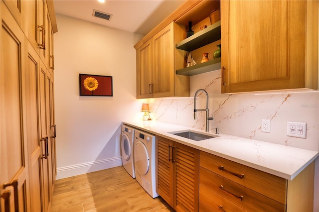 kitchen with washing machine and dryer, decorative backsplash, sink, and light hardwood / wood-style floors