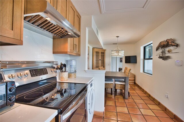 kitchen with stainless steel range with electric stovetop, an inviting chandelier, wall chimney range hood, hanging light fixtures, and light tile patterned flooring