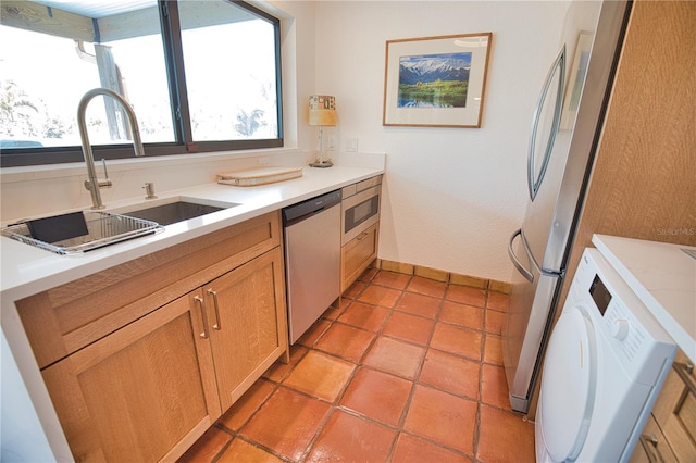 kitchen featuring light tile patterned flooring, washer / dryer, sink, and appliances with stainless steel finishes