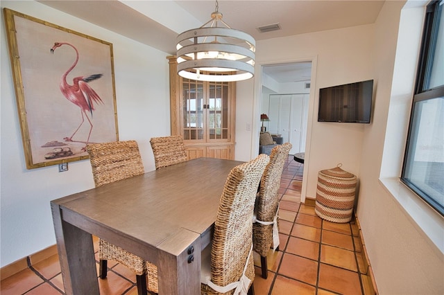 tiled dining room with a chandelier