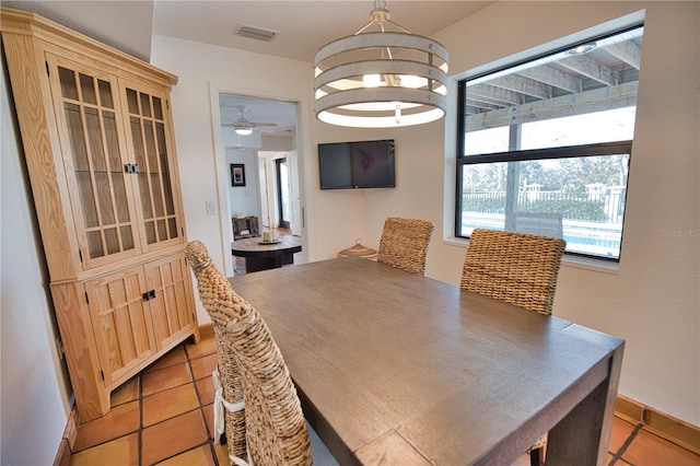 tiled dining room with ceiling fan with notable chandelier