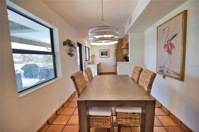 tiled dining area with sink and an inviting chandelier