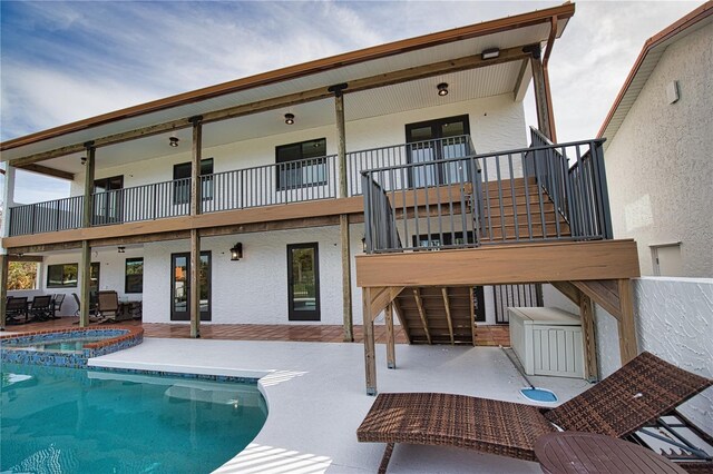 rear view of house with a swimming pool with hot tub and a patio