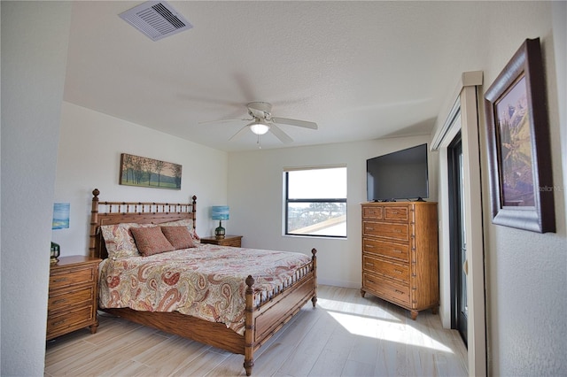 bedroom featuring ceiling fan, light hardwood / wood-style floors, and a textured ceiling