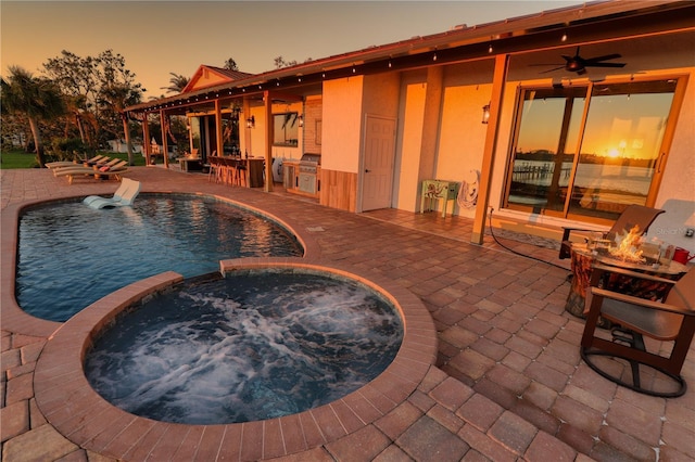 pool at dusk with an in ground hot tub, a patio, area for grilling, and ceiling fan