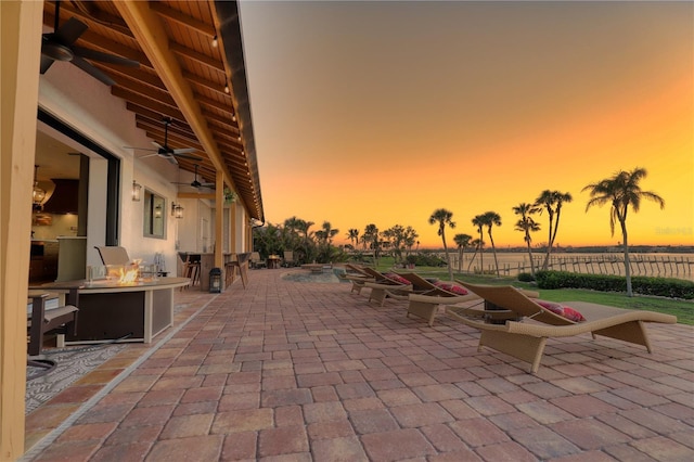 patio terrace at dusk with ceiling fan and an outdoor fire pit