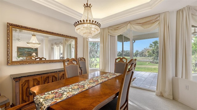 dining area with carpet flooring, a raised ceiling, plenty of natural light, and a notable chandelier