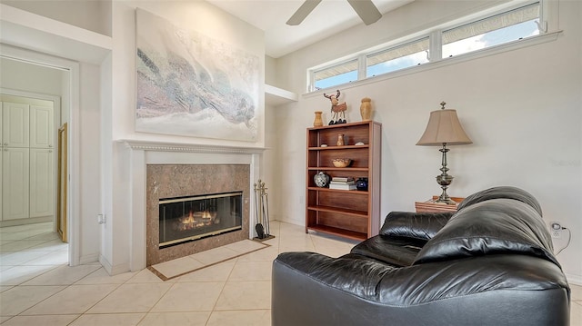 living room featuring ceiling fan, light tile patterned flooring, and a high end fireplace