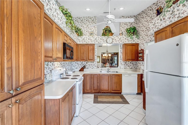 kitchen featuring sink, hanging light fixtures, white appliances, light tile patterned floors, and ceiling fan with notable chandelier