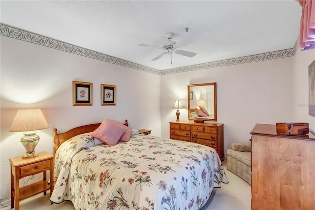 carpeted bedroom featuring ceiling fan and a textured ceiling