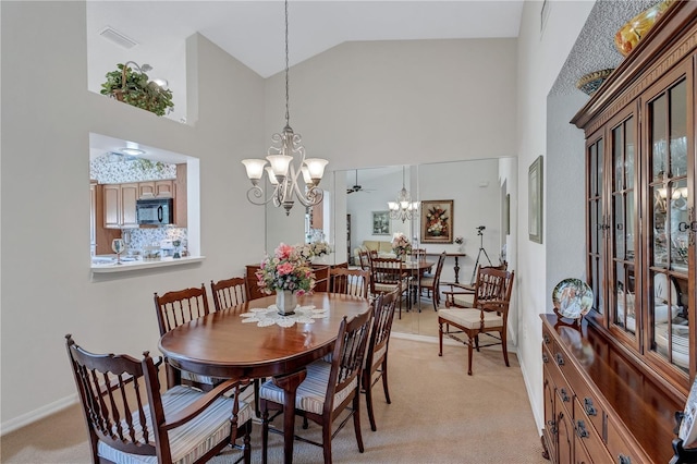 carpeted dining area with ceiling fan with notable chandelier and high vaulted ceiling