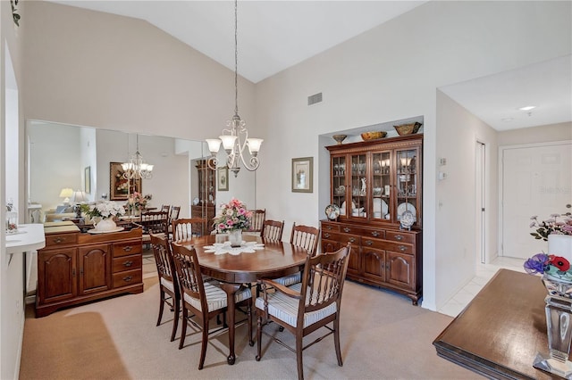 carpeted dining area with a notable chandelier and high vaulted ceiling