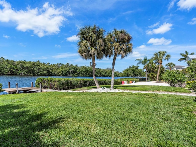 view of home's community with a lawn, a water view, and a dock