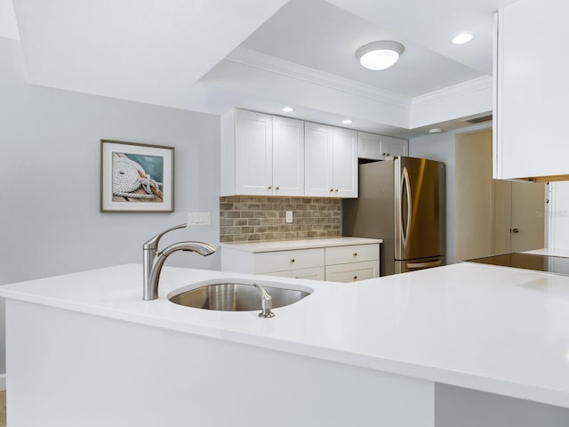 kitchen featuring decorative backsplash, crown molding, sink, white cabinets, and stainless steel refrigerator