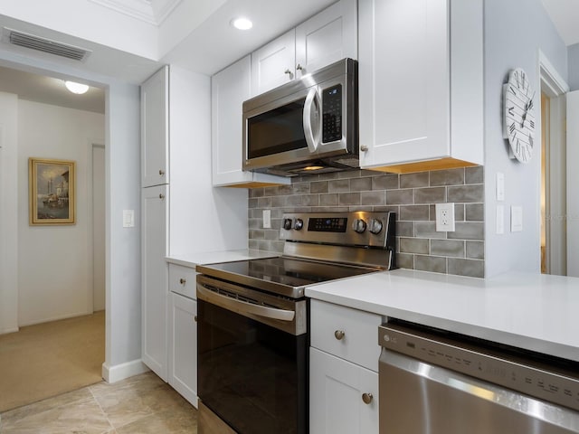 kitchen featuring decorative backsplash, light tile patterned floors, stainless steel appliances, and white cabinetry