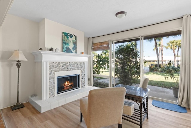 living area featuring light wood-type flooring and a tiled fireplace