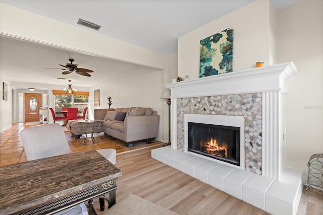 living room featuring ceiling fan, a fireplace, and light wood-type flooring