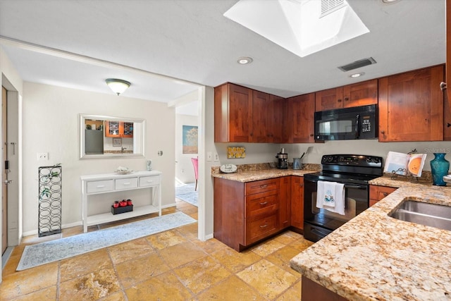 kitchen featuring light stone countertops, sink, and black appliances