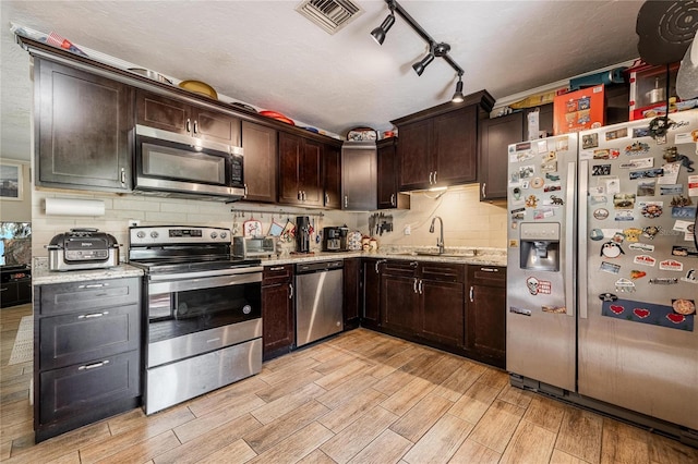 kitchen featuring sink, light wood-type flooring, light stone counters, dark brown cabinetry, and stainless steel appliances