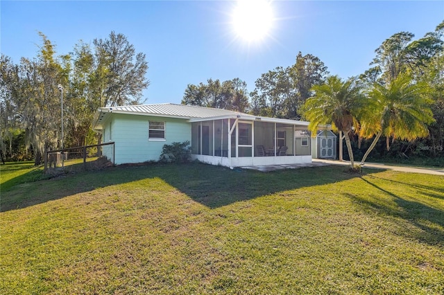 rear view of house featuring a sunroom, a storage shed, and a lawn