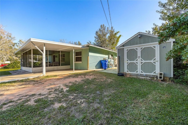 back of house with a yard, a storage unit, and a sunroom