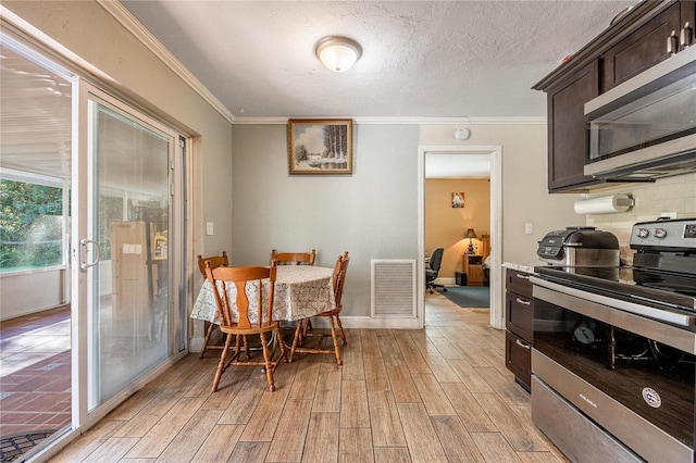 dining room featuring a textured ceiling, light wood-type flooring, and crown molding