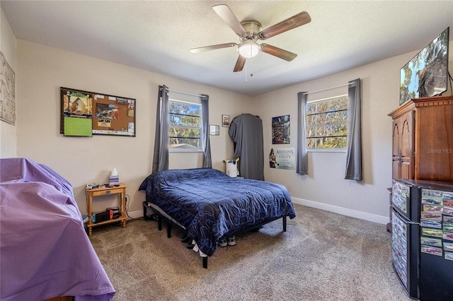 carpeted bedroom featuring ceiling fan and a textured ceiling