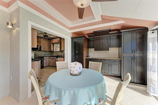 tiled dining space featuring ceiling fan, ornamental molding, sink, and a tray ceiling