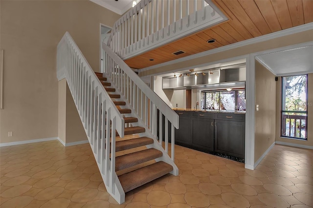 staircase with crown molding, a wealth of natural light, and wooden ceiling